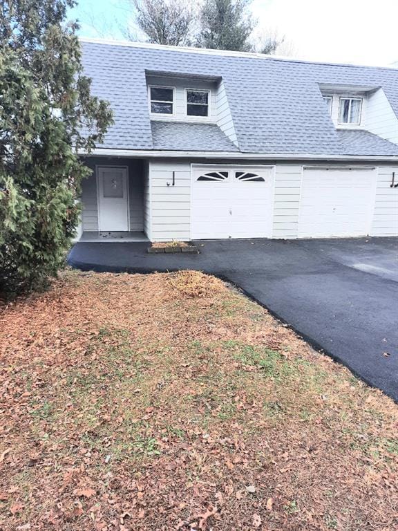 view of front facade with driveway, a shingled roof, and an attached garage