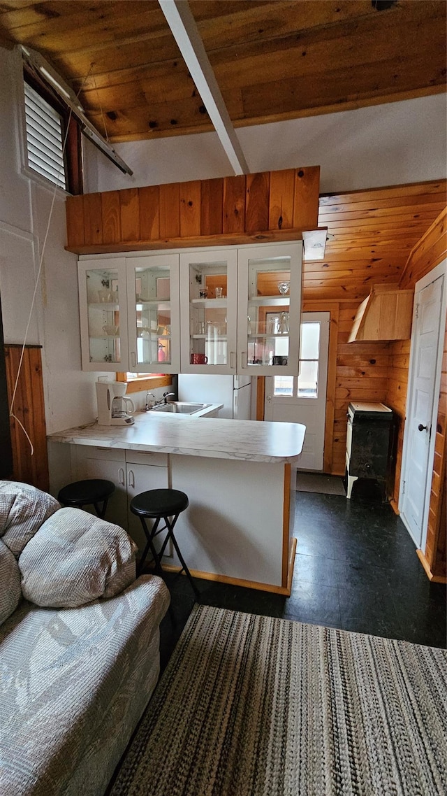 kitchen with a kitchen bar, kitchen peninsula, wooden ceiling, and a wood stove