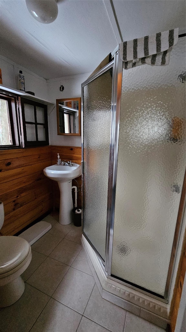 bathroom featuring tile patterned flooring, toilet, walk in shower, and wood walls