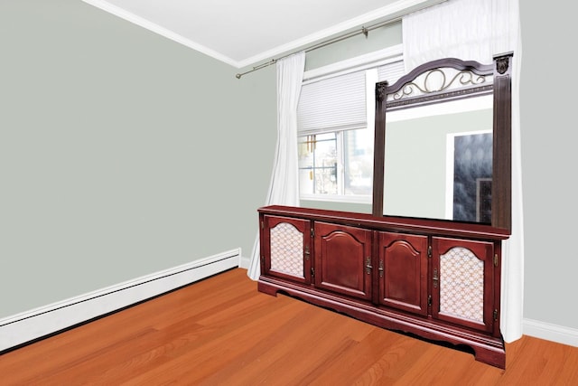 interior space with light wood-type flooring, crown molding, and a baseboard heating unit