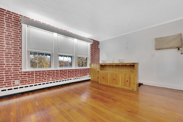 spare room with hardwood / wood-style flooring, brick wall, and a baseboard radiator