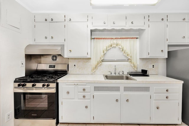 kitchen with stainless steel gas range oven, backsplash, sink, range hood, and white cabinetry