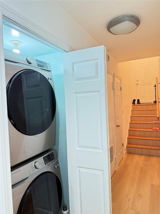 washroom featuring stacked washing maching and dryer and light wood-type flooring