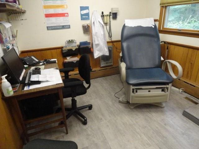 office area featuring wood walls, baseboard heating, and light hardwood / wood-style flooring