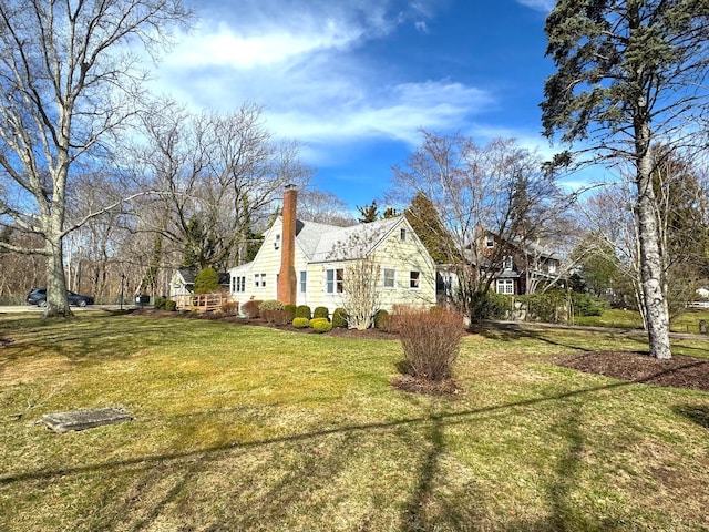 view of side of home featuring a lawn and a chimney