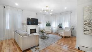 living room featuring wood-type flooring, baseboard heating, and an inviting chandelier