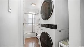 laundry area with dark wood-type flooring and stacked washer and clothes dryer