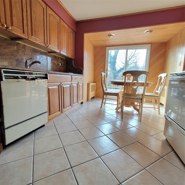 kitchen with decorative backsplash, radiator heating unit, white appliances, and wooden walls