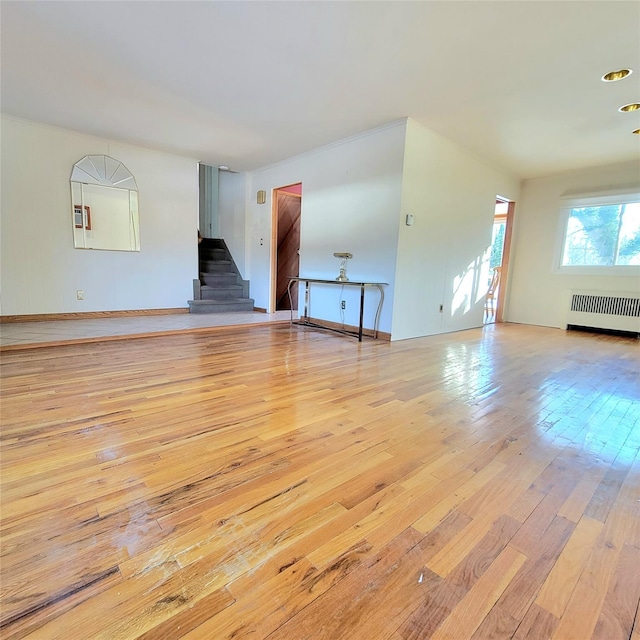 unfurnished living room featuring radiator heating unit and light hardwood / wood-style flooring