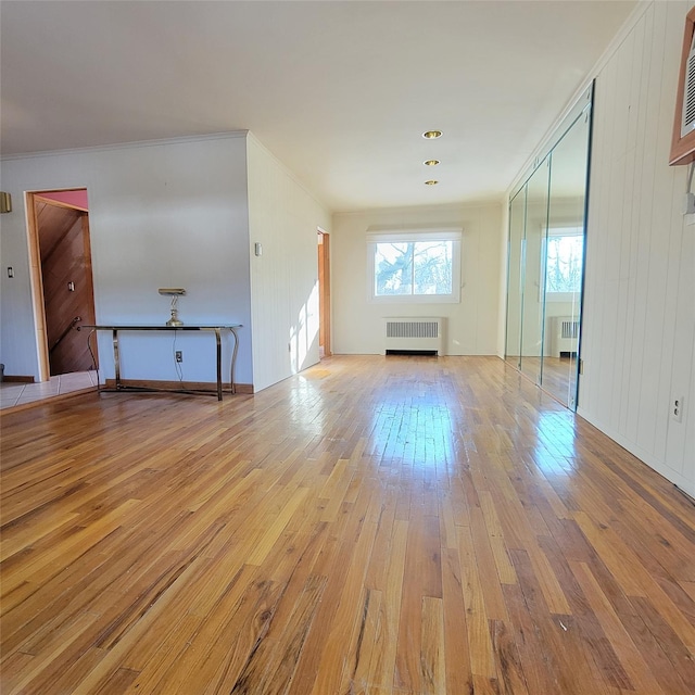 unfurnished living room featuring radiator, crown molding, and light hardwood / wood-style floors