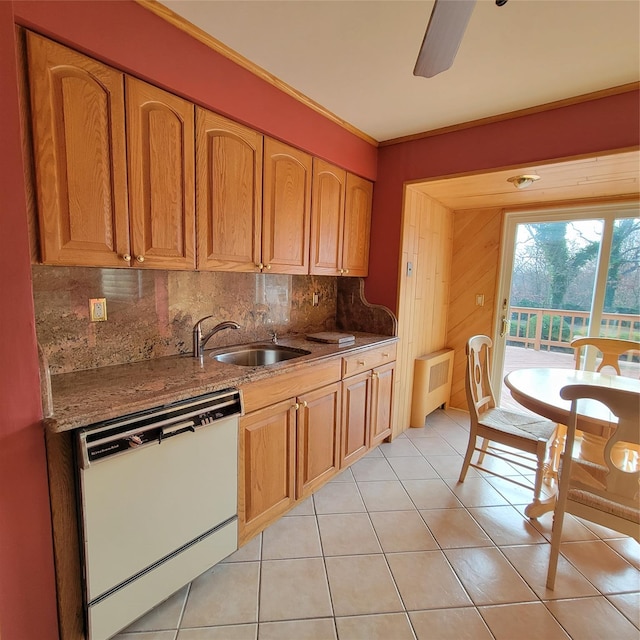 kitchen with light tile patterned flooring, sink, stone countertops, white dishwasher, and radiator