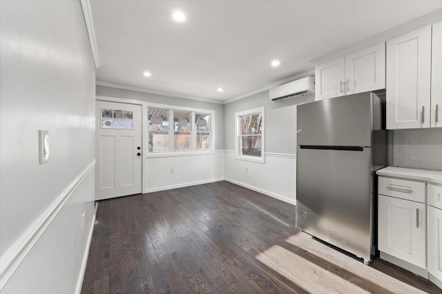 kitchen featuring a wall mounted air conditioner, backsplash, white cabinets, dark hardwood / wood-style floors, and stainless steel refrigerator