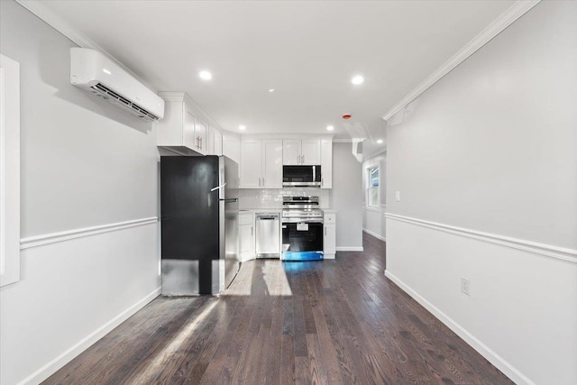 kitchen featuring a wall mounted air conditioner, appliances with stainless steel finishes, white cabinetry, and crown molding