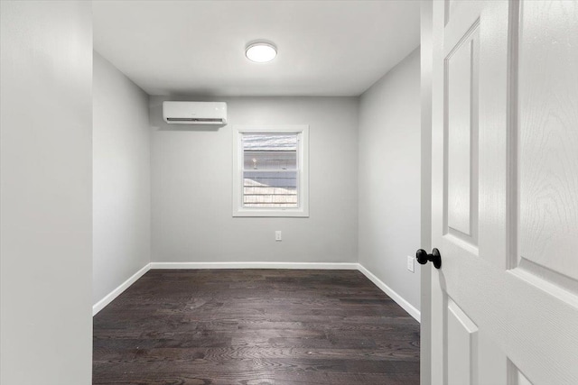 unfurnished room with an AC wall unit and dark wood-type flooring