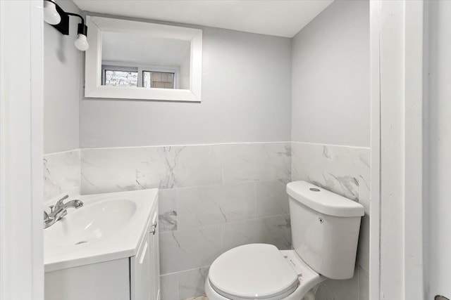 bathroom with vanity, toilet, and tile walls