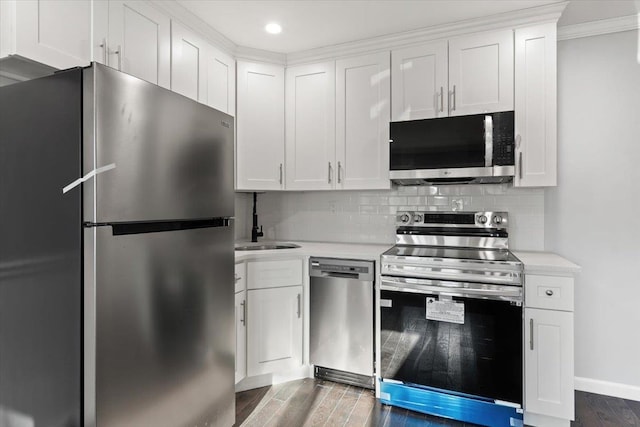 kitchen featuring dark wood-type flooring, appliances with stainless steel finishes, decorative backsplash, and white cabinets