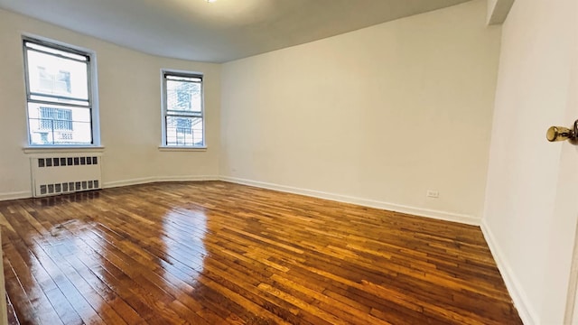 empty room with radiator and dark hardwood / wood-style flooring