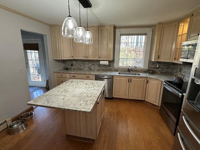 kitchen featuring sink, a center island, wood-type flooring, decorative light fixtures, and appliances with stainless steel finishes