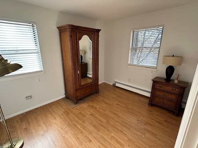 interior space with a baseboard radiator, light hardwood / wood-style flooring, and multiple windows