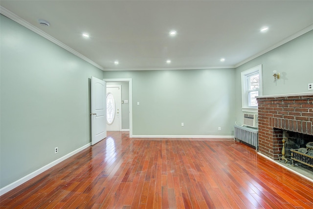 unfurnished living room with hardwood / wood-style flooring, radiator heating unit, crown molding, and a brick fireplace