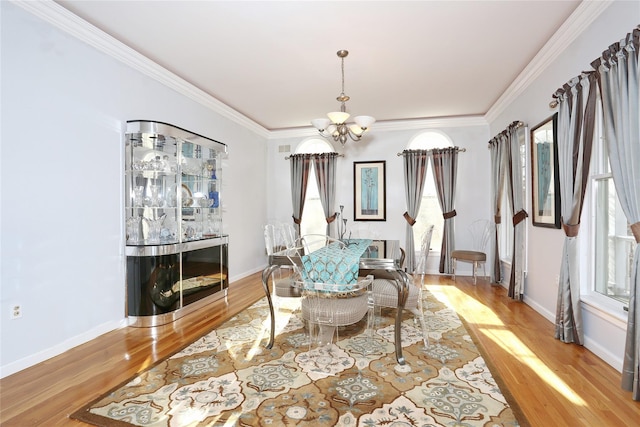 dining space with light hardwood / wood-style floors, ornamental molding, and a chandelier