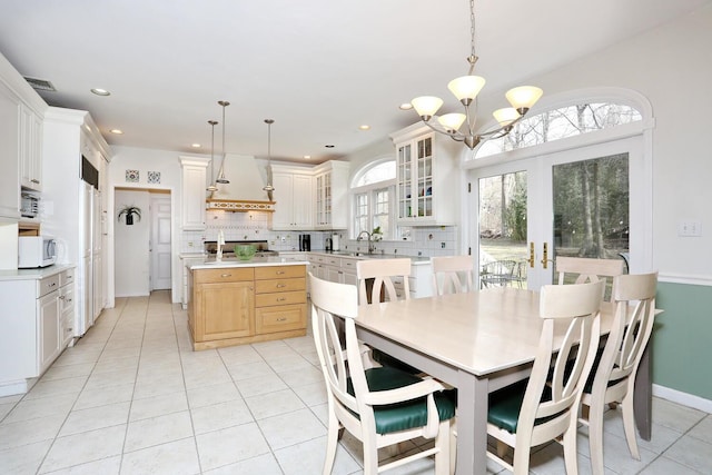 tiled dining area featuring sink, a chandelier, and french doors