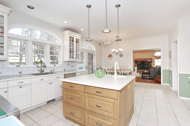 kitchen featuring a center island, light tile patterned flooring, sink, an inviting chandelier, and hanging light fixtures