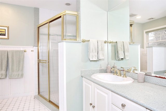 bathroom with a shower with shower door and vanity