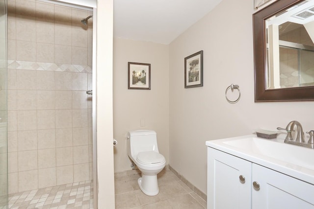 bathroom featuring toilet, tile patterned flooring, a tile shower, and vanity