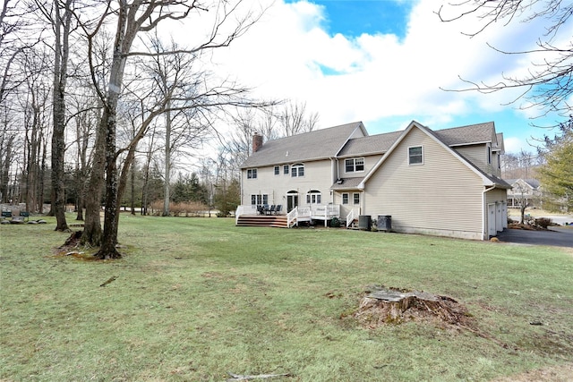 back of house featuring a deck, a yard, and a garage