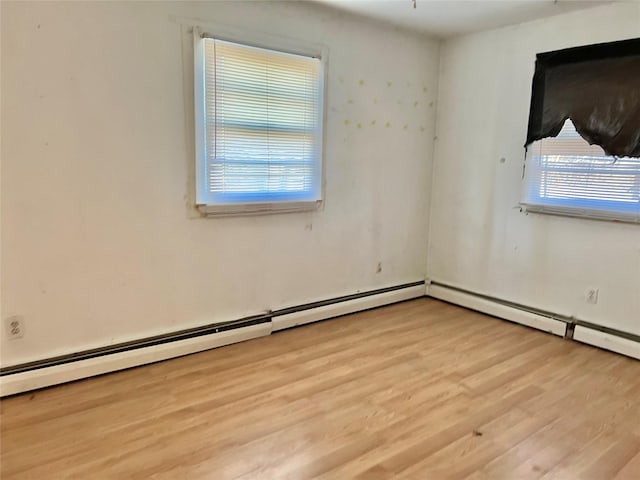 unfurnished room with baseboard heating and light hardwood / wood-style flooring