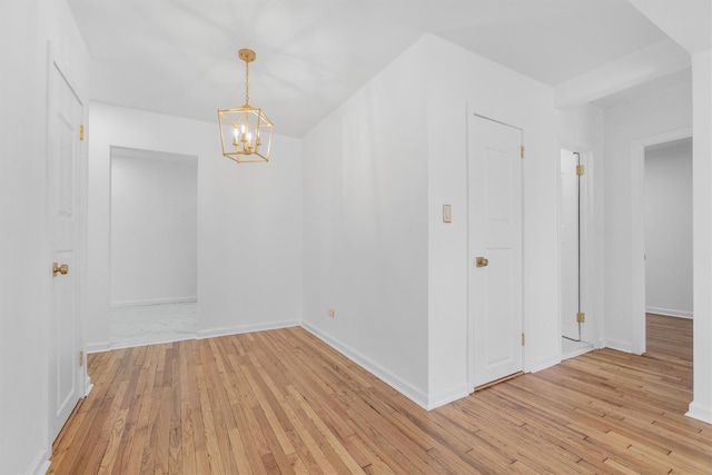 empty room featuring light wood-type flooring and a chandelier