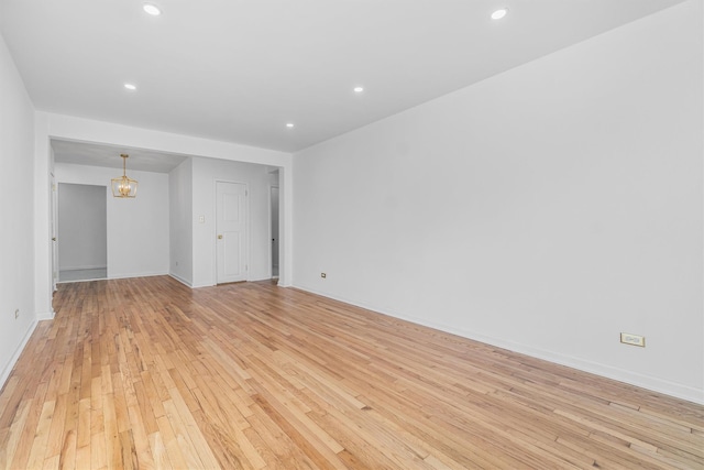 unfurnished room featuring a chandelier and light hardwood / wood-style floors