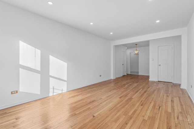 unfurnished living room with a chandelier and light hardwood / wood-style floors