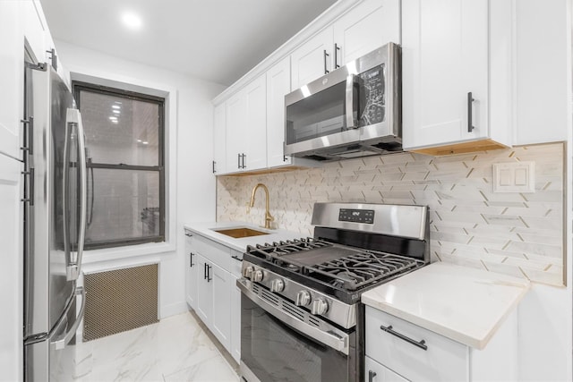 kitchen with backsplash, stainless steel appliances, white cabinetry, and sink