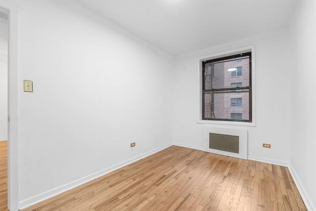 unfurnished room featuring light wood-type flooring and radiator heating unit