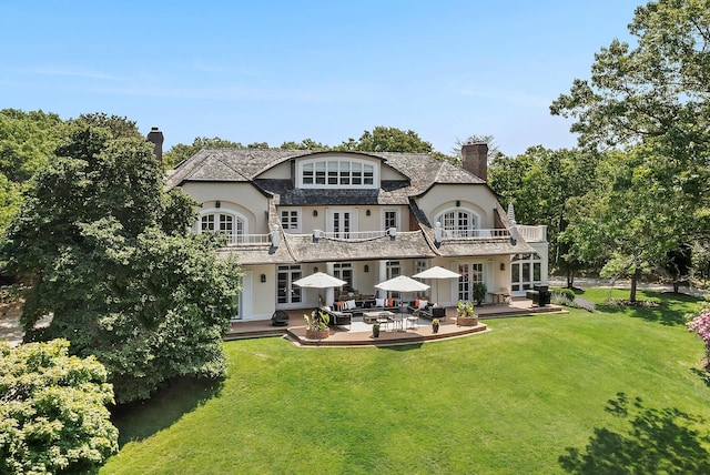 back of property with a balcony, a yard, a patio, and french doors