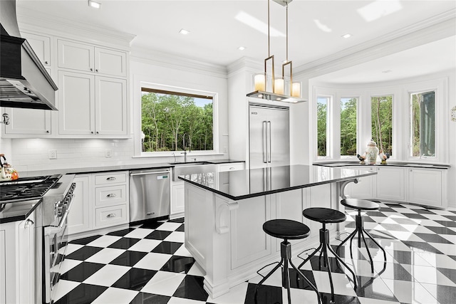 kitchen featuring a center island, range hood, decorative light fixtures, white cabinets, and appliances with stainless steel finishes