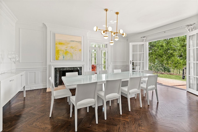 dining room with dark parquet flooring, french doors, ornamental molding, a premium fireplace, and a notable chandelier