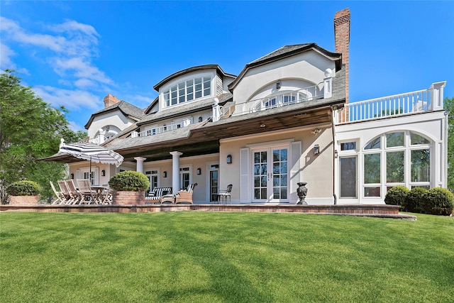 back of house featuring a lawn, a balcony, and a patio