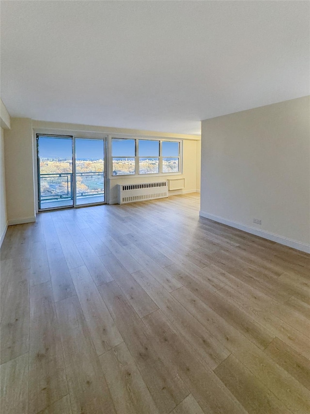 unfurnished room featuring light wood-type flooring and radiator heating unit