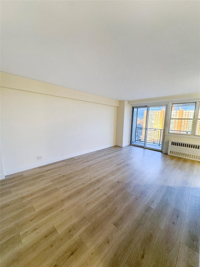 empty room with light wood-type flooring and radiator