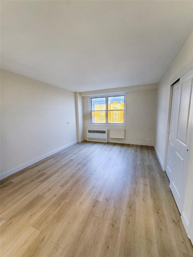 empty room featuring radiator and light hardwood / wood-style floors