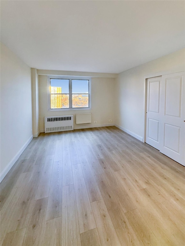 unfurnished room with light hardwood / wood-style floors and radiator