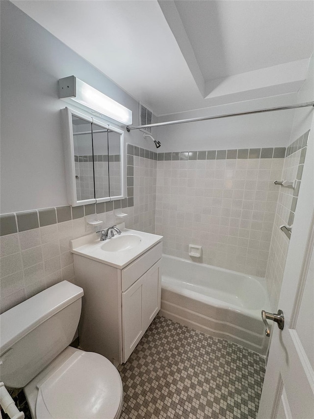 full bathroom featuring tiled shower / bath combo, toilet, tile walls, and vanity