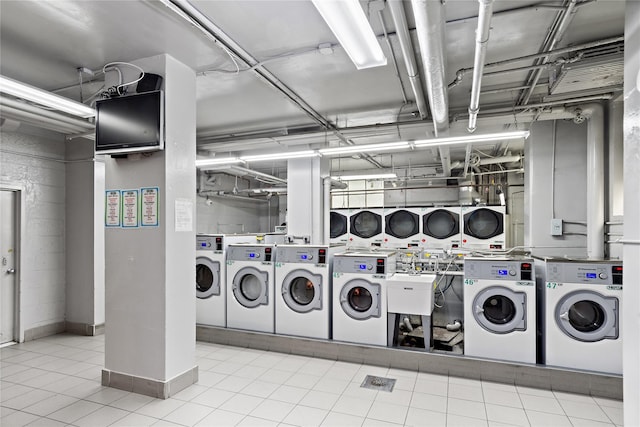 clothes washing area featuring light tile patterned floors, stacked washing maching and dryer, and washing machine and clothes dryer