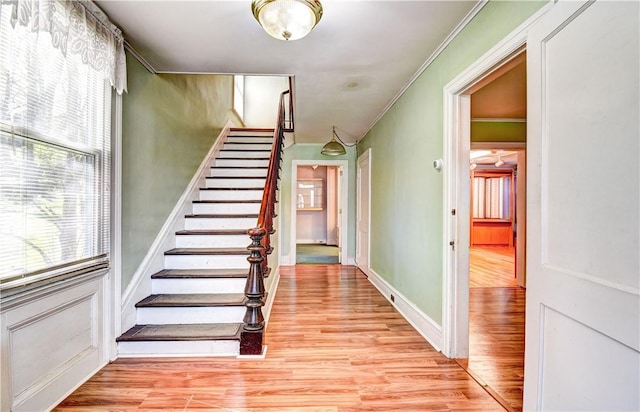 staircase with hardwood / wood-style flooring and crown molding