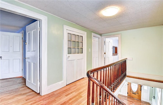 hallway with light hardwood / wood-style flooring and a textured ceiling