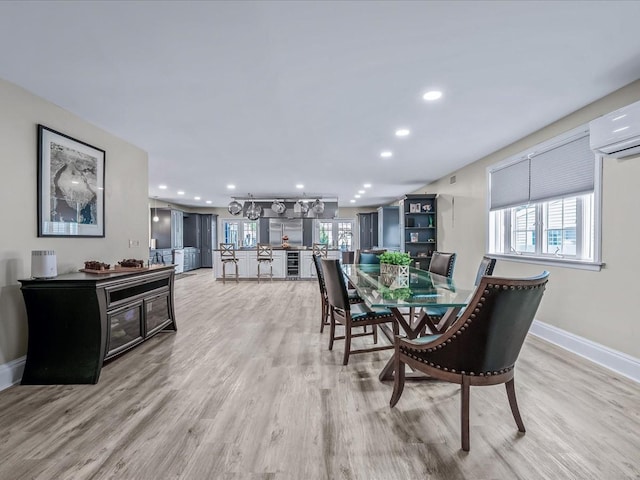 dining room featuring light hardwood / wood-style flooring, plenty of natural light, and a wall unit AC