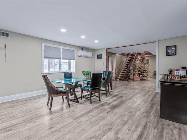 dining space with light wood-type flooring and an AC wall unit